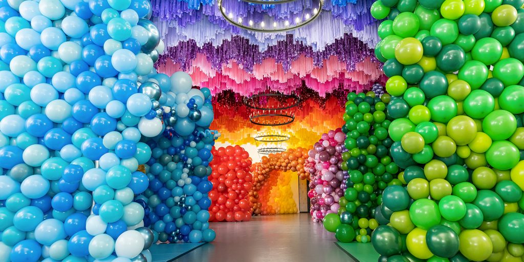 Rainbow colorful large-scale balloon decoration that encapsulates the walls and ceilings.