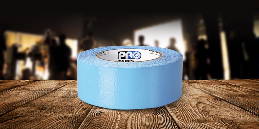 A roll of Dual-Tack Floor Secure Tape features a high tack adhesive side, a low tack adhesive, and a blue removeable liner. 