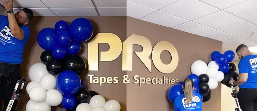 Dellon's balloon artists Dolly and Eddie, crafting a blue, white, and black balloon garland created with Pro Tapes products at the Pro Tapes office. 