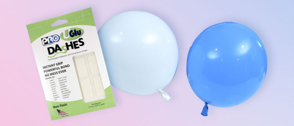 UGlu Dashes sits next to latex balloons in the color white and blue. 