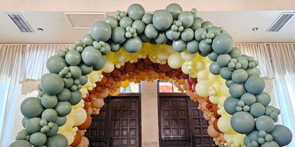 A grand balloon arch featuring balloons of various sizes. The arch towers high above a doorway. 